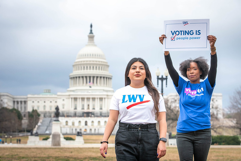 LWVUS staff in front of the US Capitol building. One staff member is holding a voting is people power sign