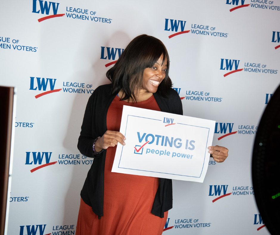 Woman standing in from of a step and repeat with the red and blue 