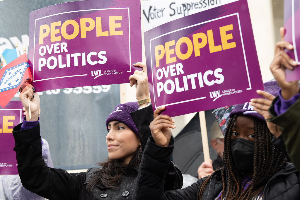 LWV member Isamar Garcia-Hernandez holding a sign that says People Over Politics at a rally